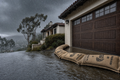Hydrated StormBag burlap sandbag barrier holding back atmospheric river floodwater at a California garage door