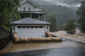 Hydrated StormBag burlap sandbag barrier protecting a Mid-Atlantic home garage during a flash flood event with a creek out of its banks in the background